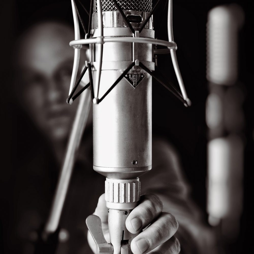Black and white photo of a hand holding a studio microphone