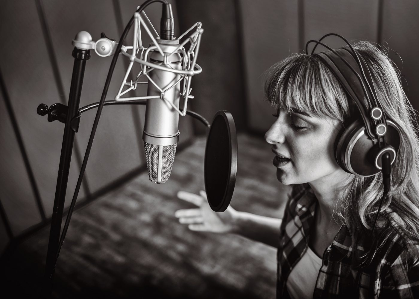 Black and white photo of a vocalist recording at the microphone